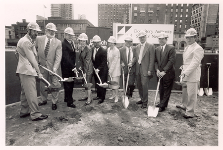 Groundbreaking ceremony with group holding shovels wearing hardhats.