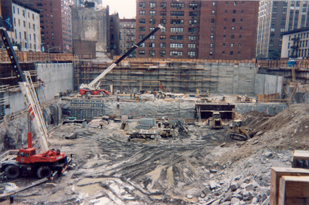 Two cranes and other construction equipment in the pit of the construction site.